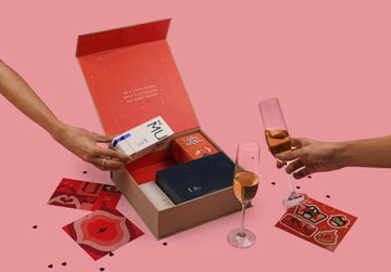 Valentines day gift box with two glasses of wine and a hand holding Glide personal jelly