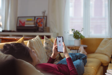 A person lying on the sofa and swiping on a dating app 