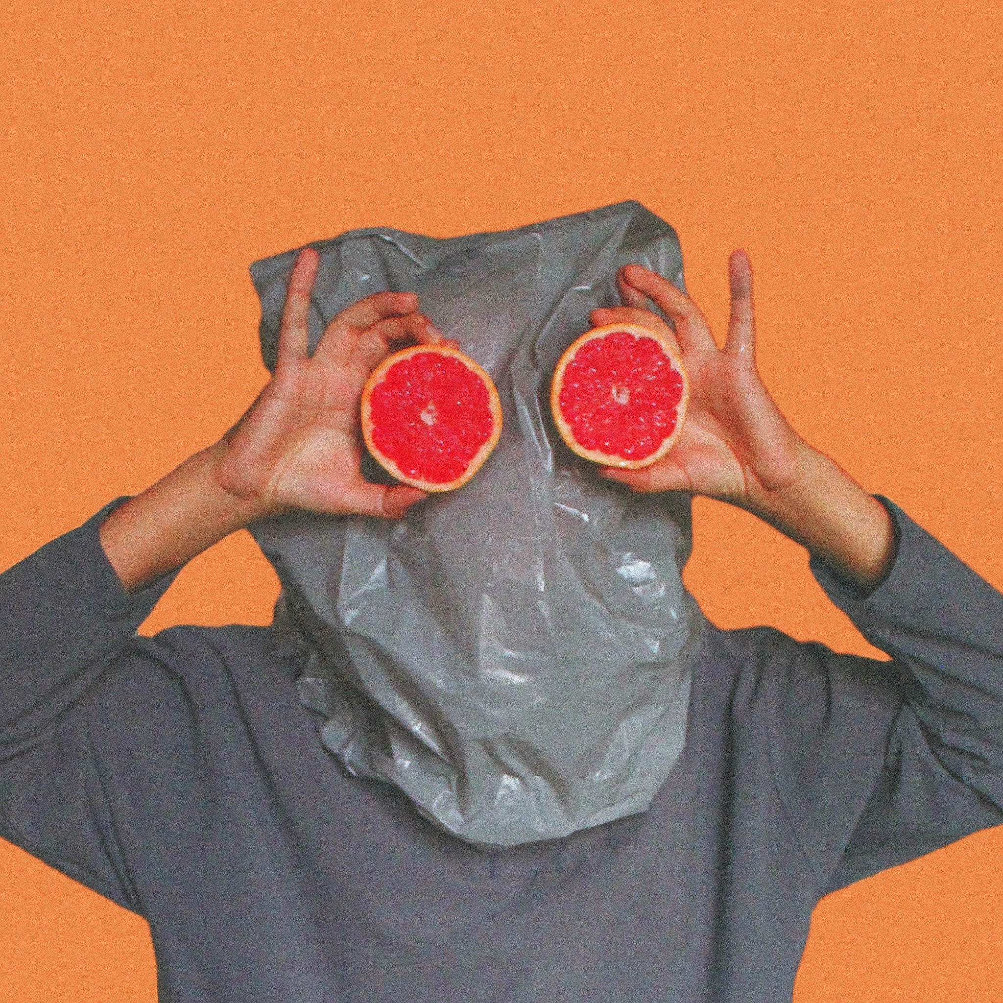 Person with bag on their head looking through oranges