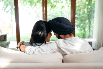 Cuddling young Indian couple resting on sofa