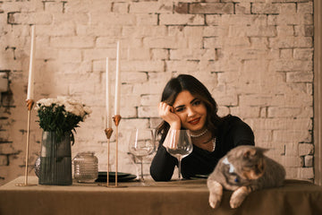 Woman in black long-sleeve dress smiling and petting a cat