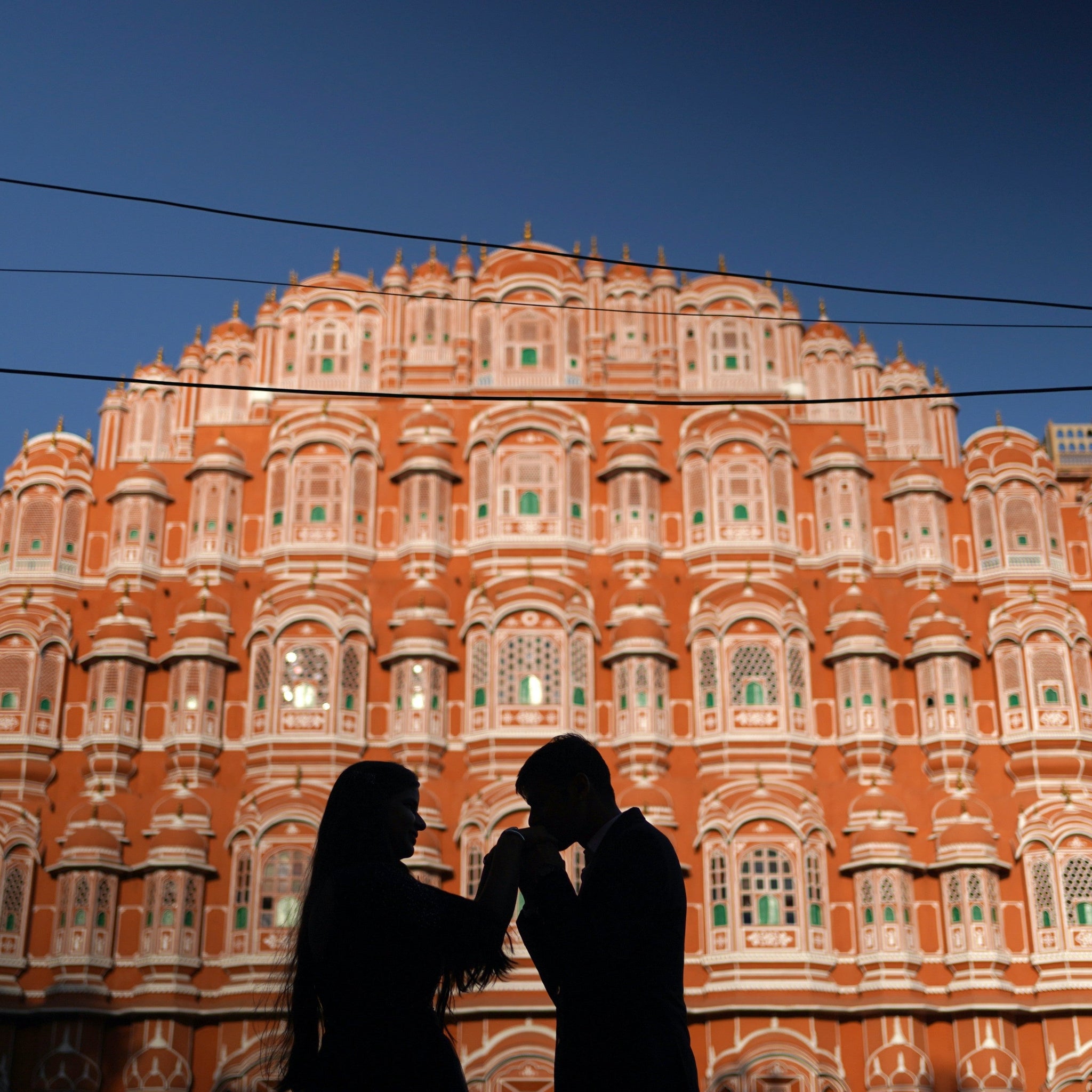 Couple standing in front of the Hawa Mahal in Jaipur, India