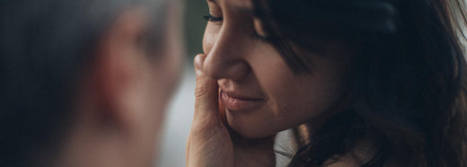 A man embracing the face of a woman with eyes closed