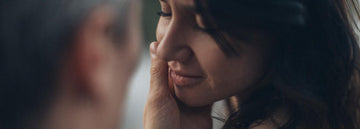 A man embracing the face of a woman with eyes closed