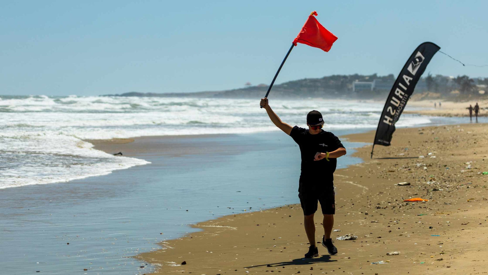 Free A Man with a Red Flag on the Beach Stock Photo