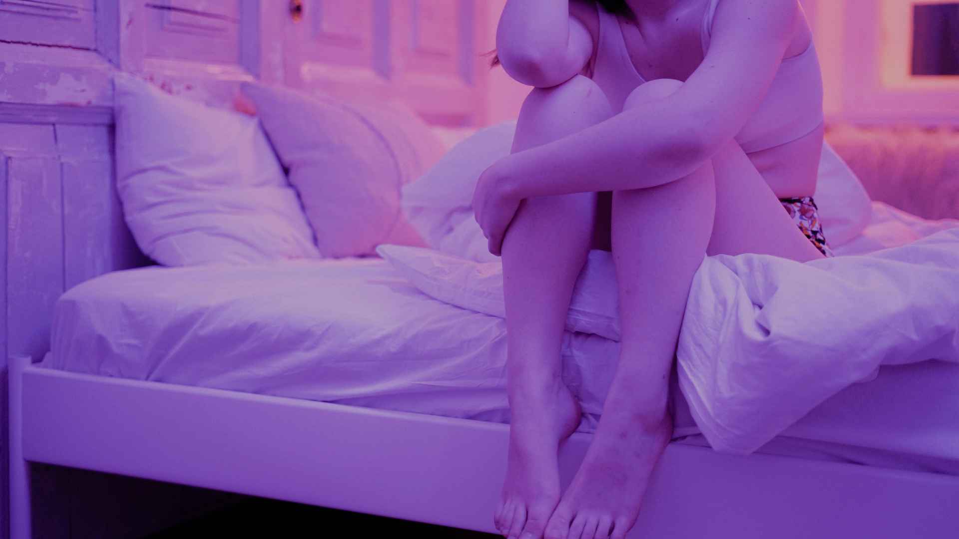 Woman Sitting on White Bed