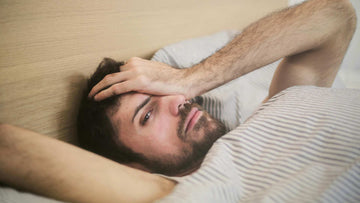 Pensive man lying in bed in morning