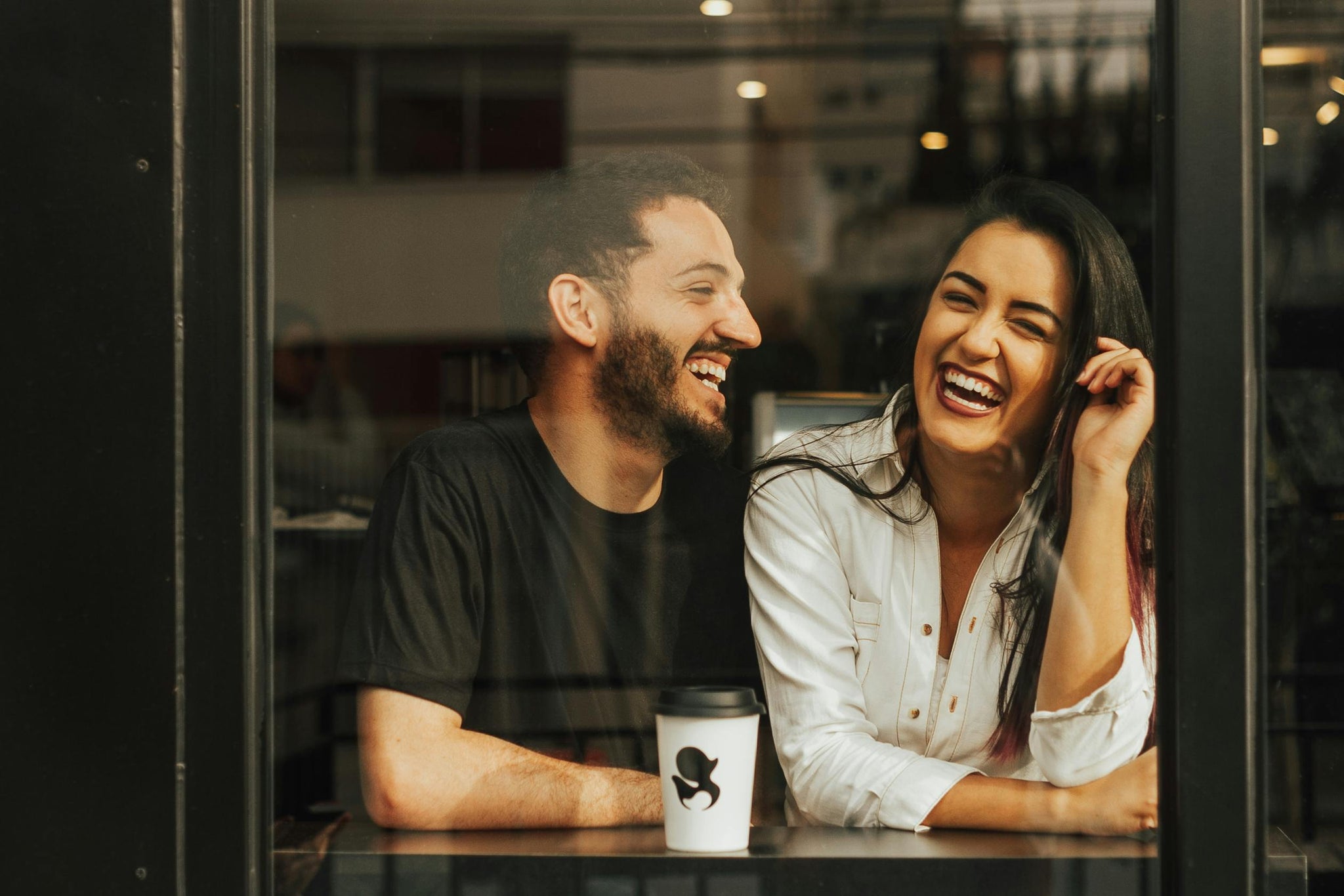 Photo of a Laughing Couple Sitting in a Cafe 