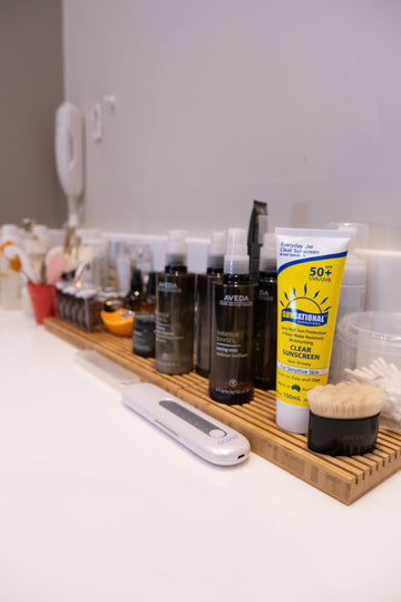 A bathroom shelf crowded with skincare bottles and tubs