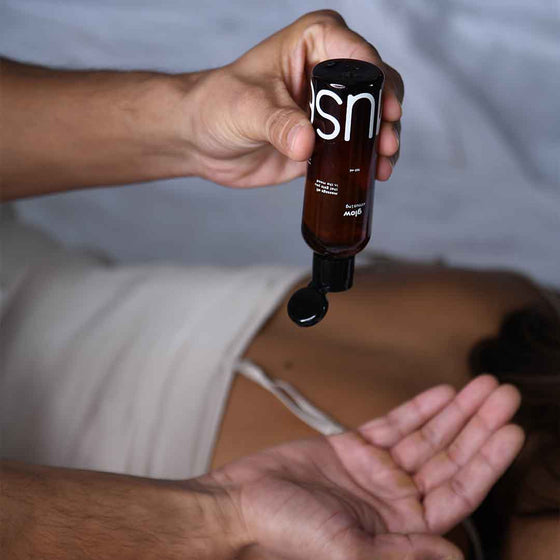 A person applying Glow Arousing massage oil to his partner