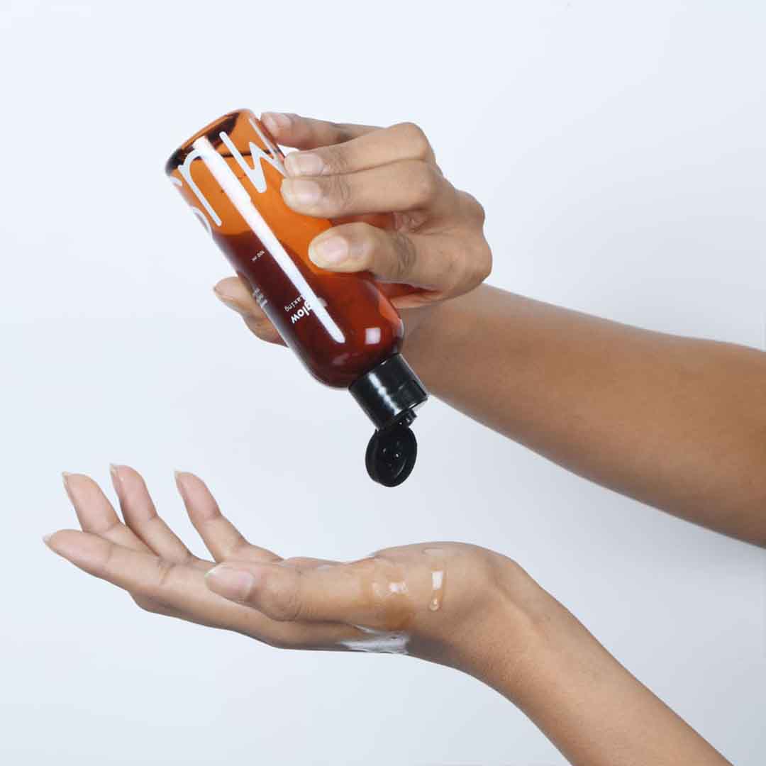 A person applying Glow Arousing massage oil on their hands for self-care