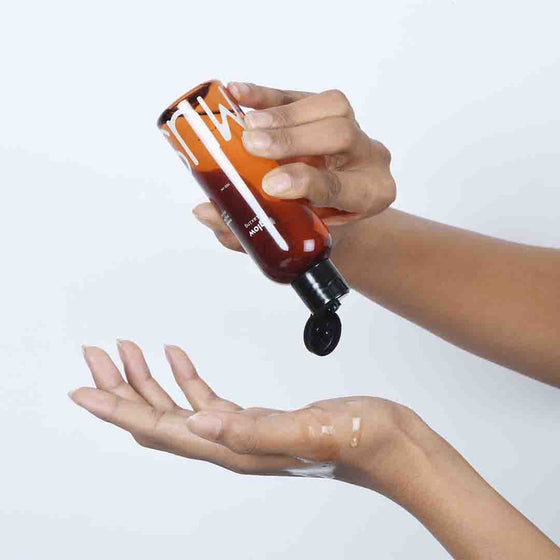 A person applying Glow Relaxing massage oil onto their hands directly from its bottle